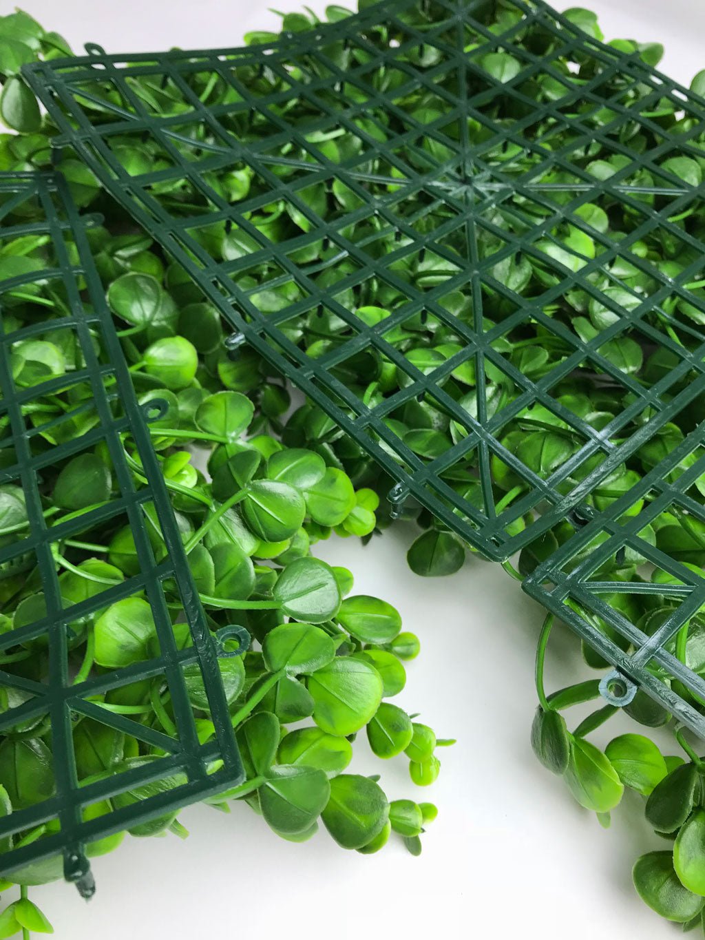 Artificial green plant wall panel with open grid frame and bright green leaf clusters