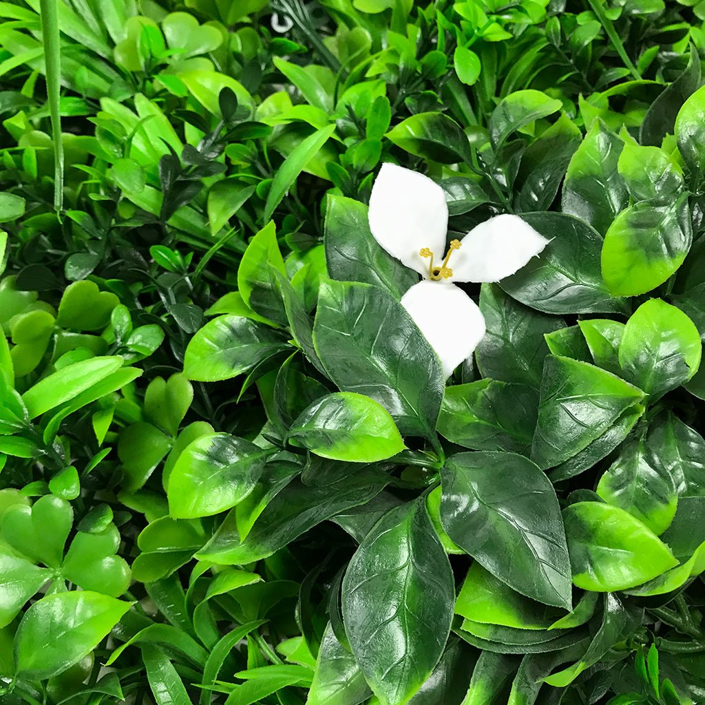 Artificial green foliage wall panel with mixed leaves and small white flowers, 100x100 cm
