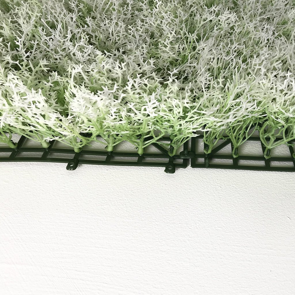 Artificial moss panel edge with dark mounting frame and dense tufted moss top.