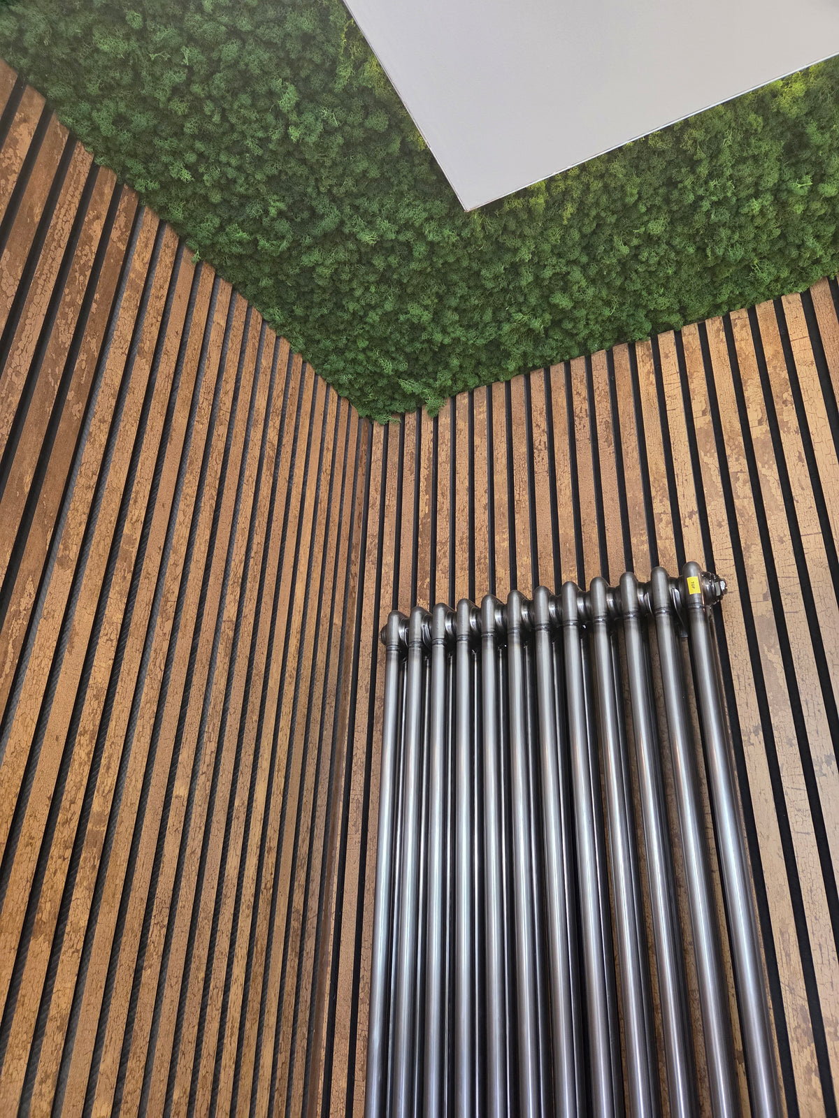 Green reindeer moss panel corner with heating pipes below