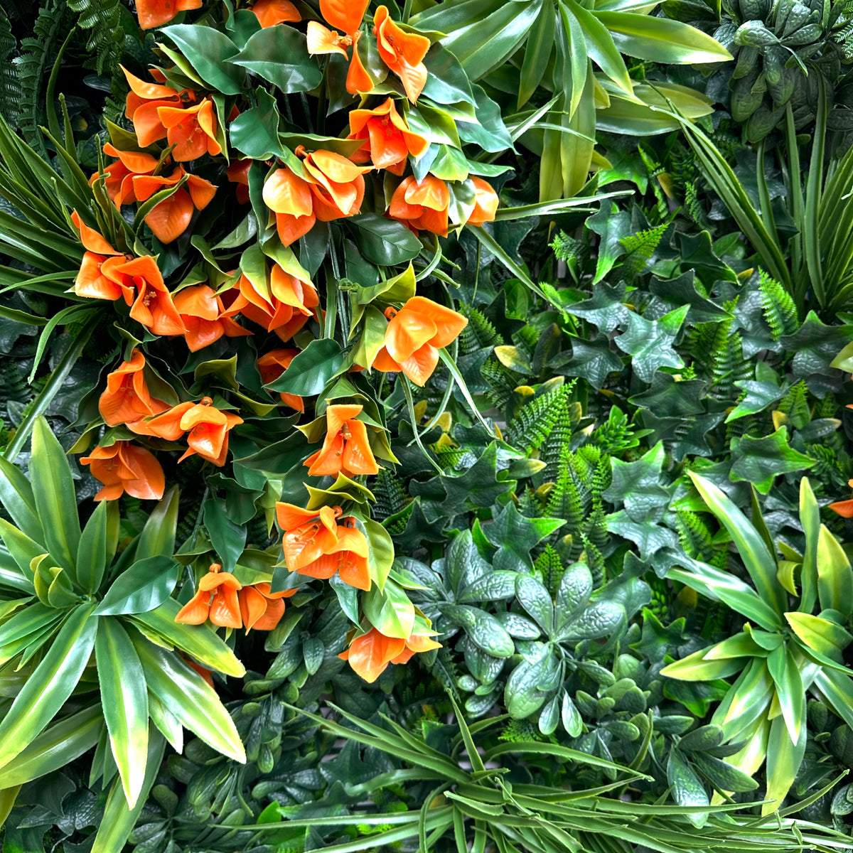 Artificial foliage wall panel close-up with variegated green leaves and orange blossoms