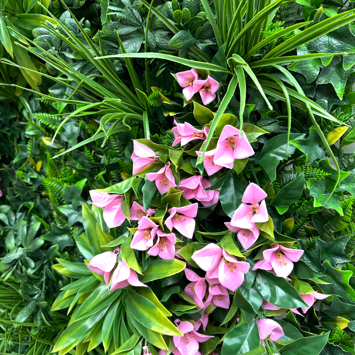 Artificial foliage wall panel close-up of pink bougainvillea blooms on green leaves