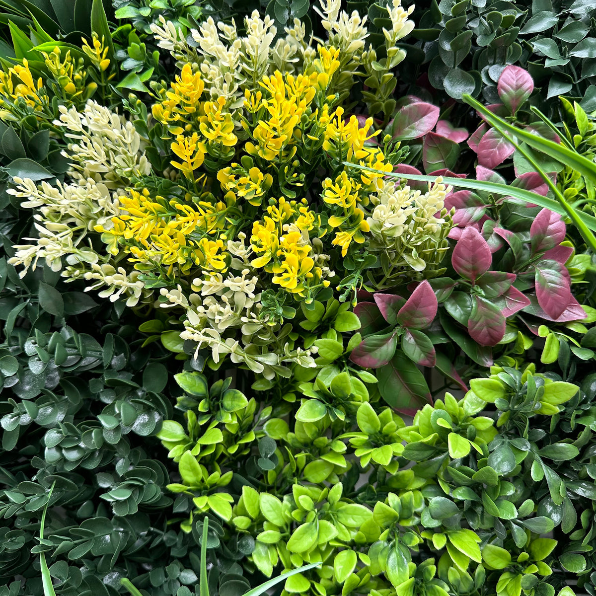 Artificial foliage wall panel with mixed green, yellow blooms, and pink leaf accents
