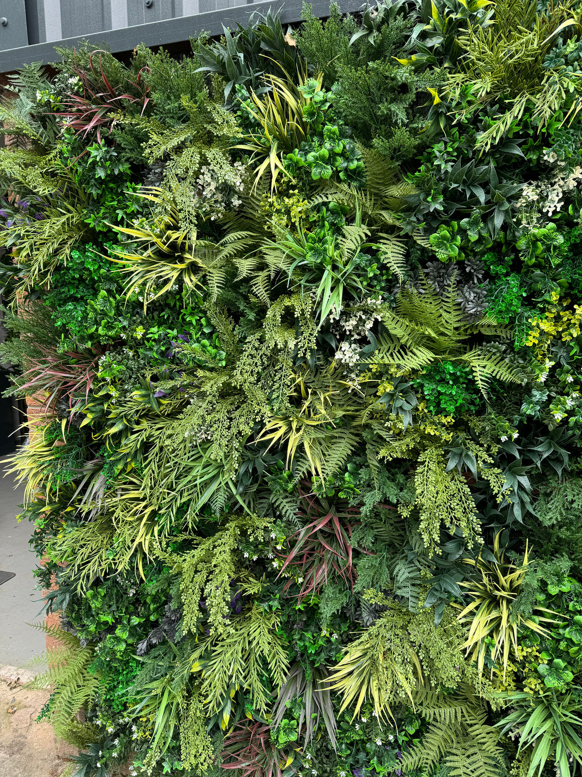 Artificial 3D plant wall panel with layered fern-like and needle-like green foliage