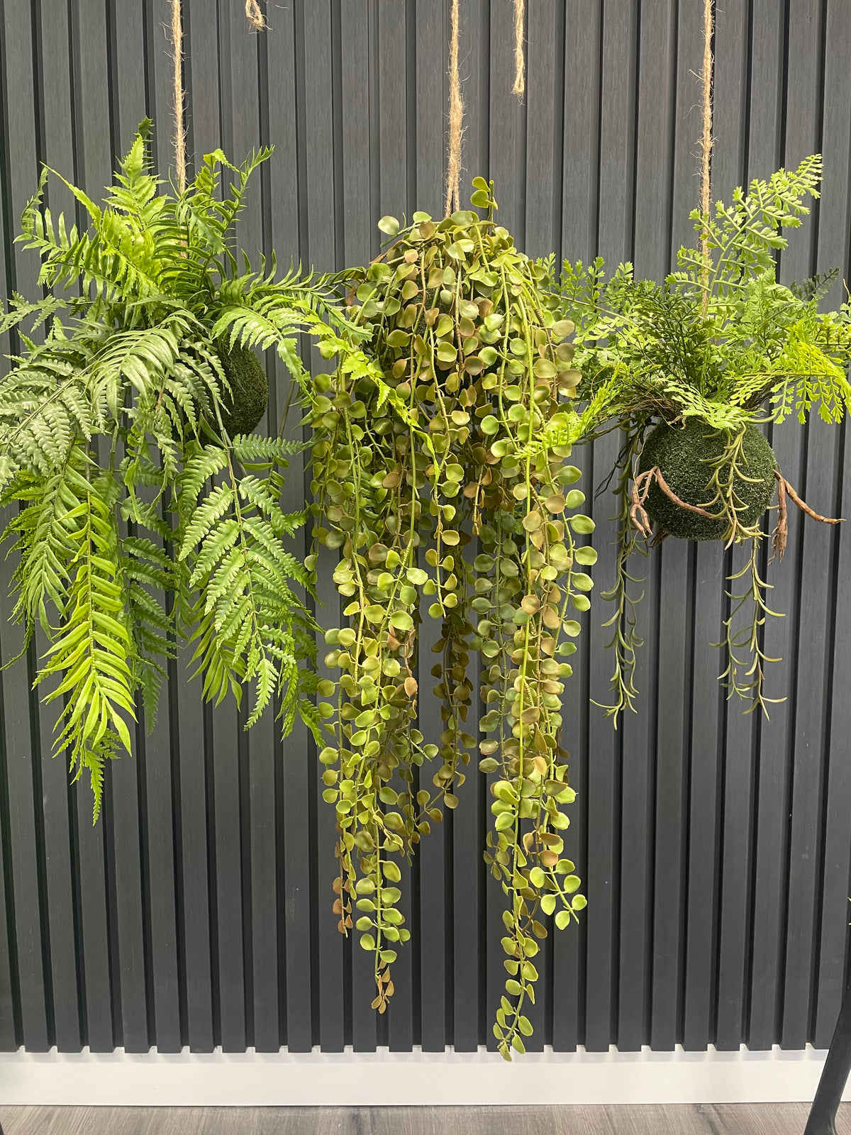 Hanging artificial trailing fern kokedama with beadlike green fronds and rope loop