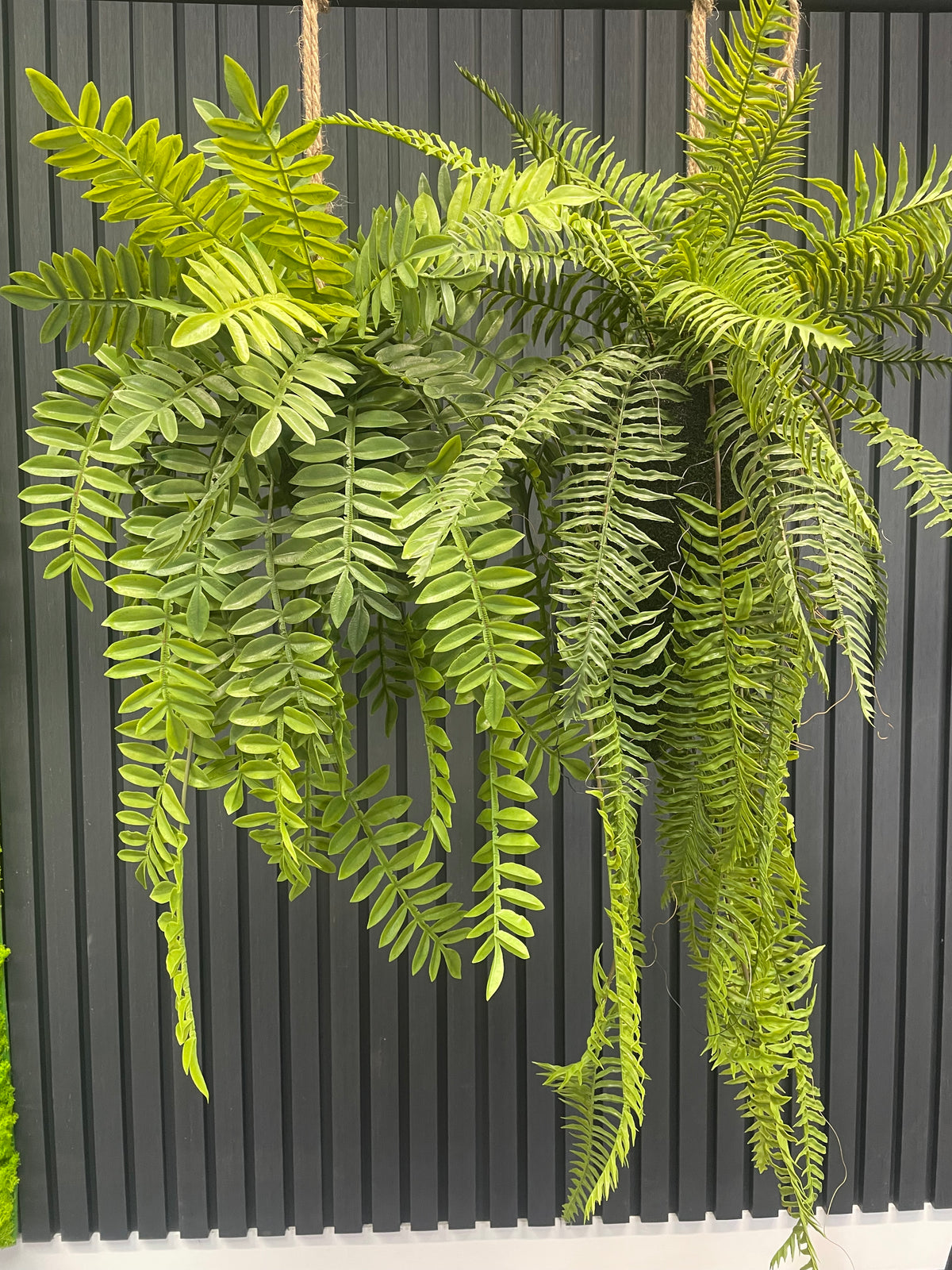 Artificial trailing fern kokedama with bright green fern fronds on a twine hanger