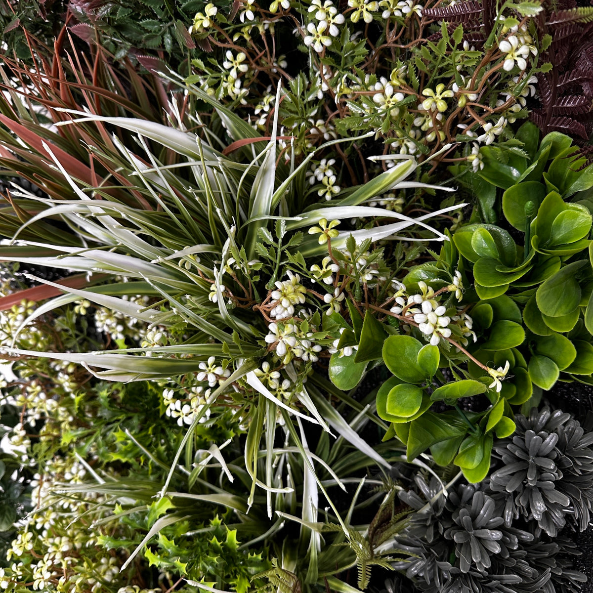 Artificial 3D plant wall closeup with white blossom-like tips and green foliage
