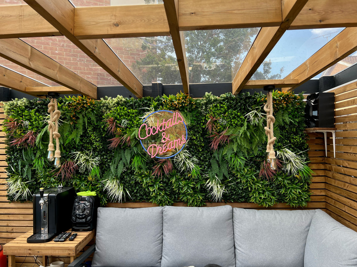 Artificial green wall panel with layered foliage and small white-yellow flower accents