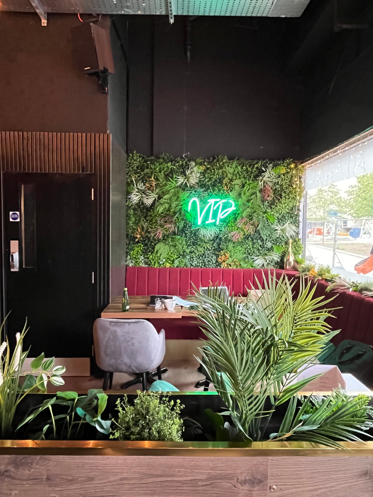 Artificial green wall panel with dense mixed greenery and red decorative flower accents