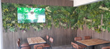 Artificial green wall panel with variegated greens of ivy, ferns, palm heads, grasses & yellow tipped privets 100x100 cm