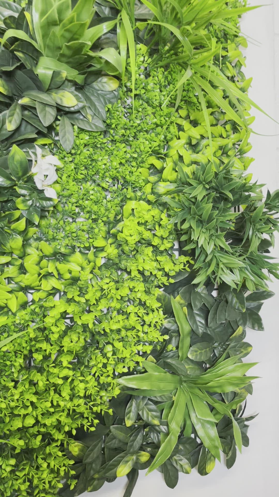 Artificial green wall panel with variegated green foliage  palms grasses eucalyptus and white flowers 100x100 cm