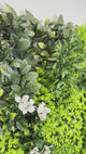 Artificial green wall panel with variegated green foliage  palms grasses eucalyptus and white flowers 100x100 cm
