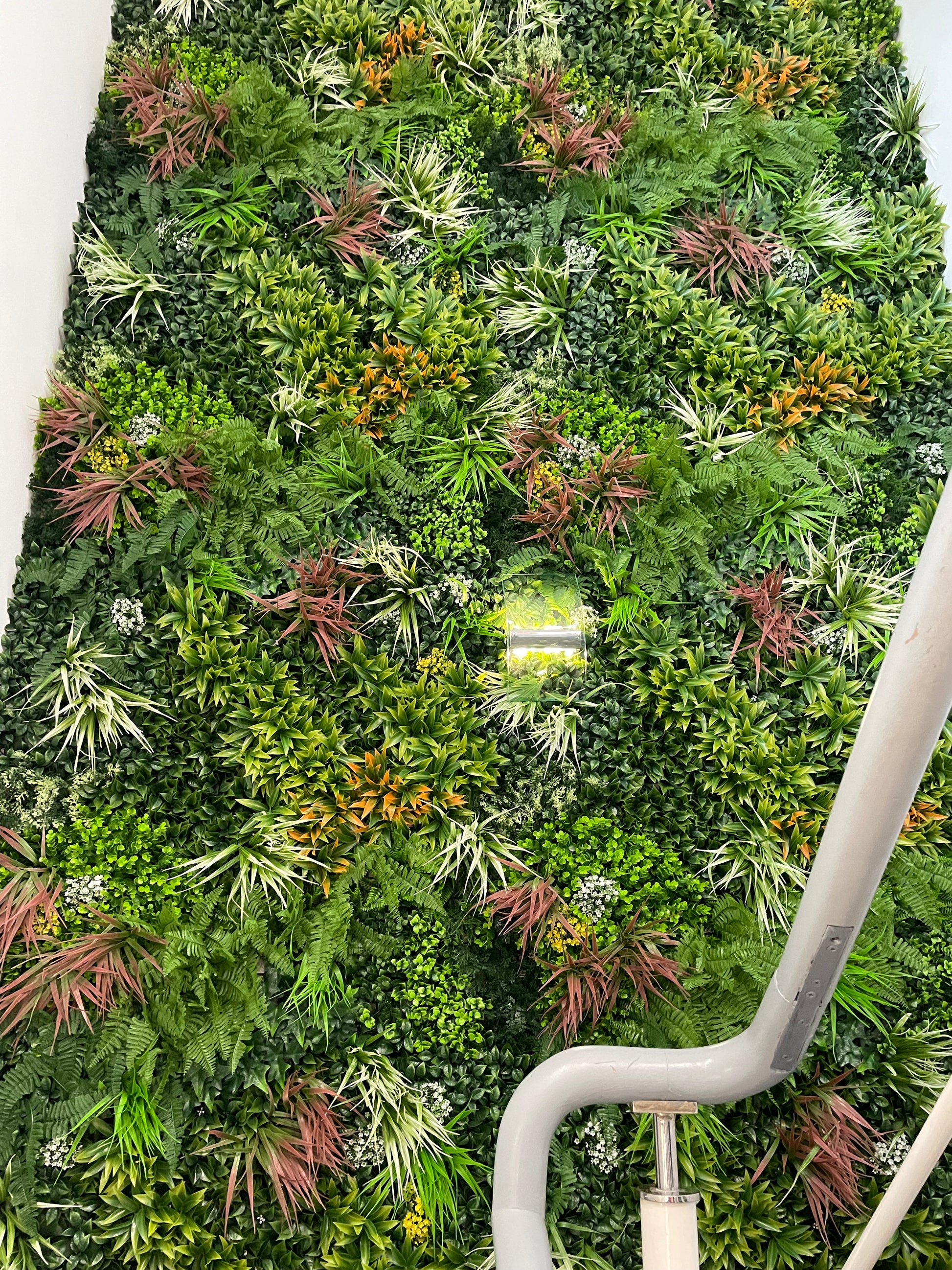 Artificial green foliage wall panel with mixed leaves and orange-red highlights