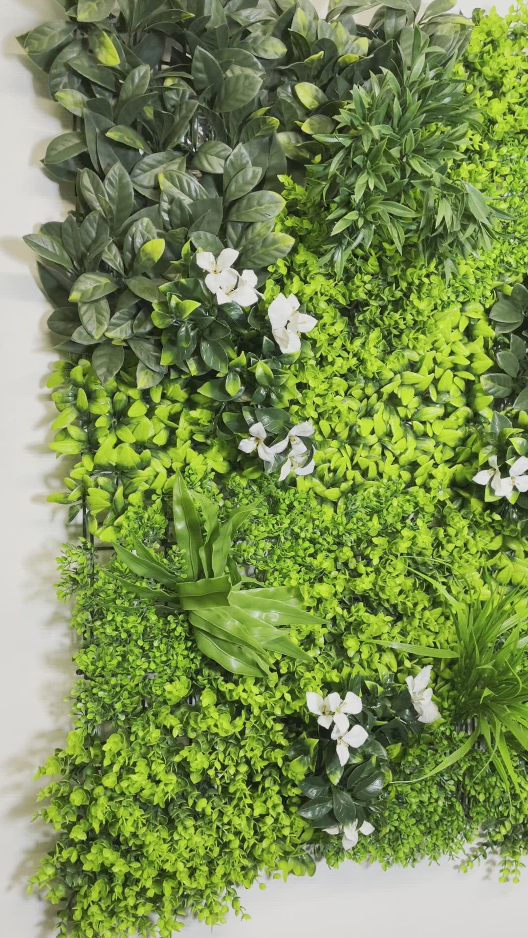 Artificial green wall panel with variegated green foliage  palms grasses eucalyptus and white flowers 100x100 cm