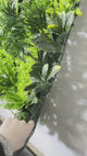 Artificial green wall panel with variegated green foliage  palms grasses eucalyptus and white flowers 100x100 cm