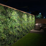 Artificial green wall panel with variegated greens of ivy, ferns, palm heads, grasses & small purple flowers  100x100 cm