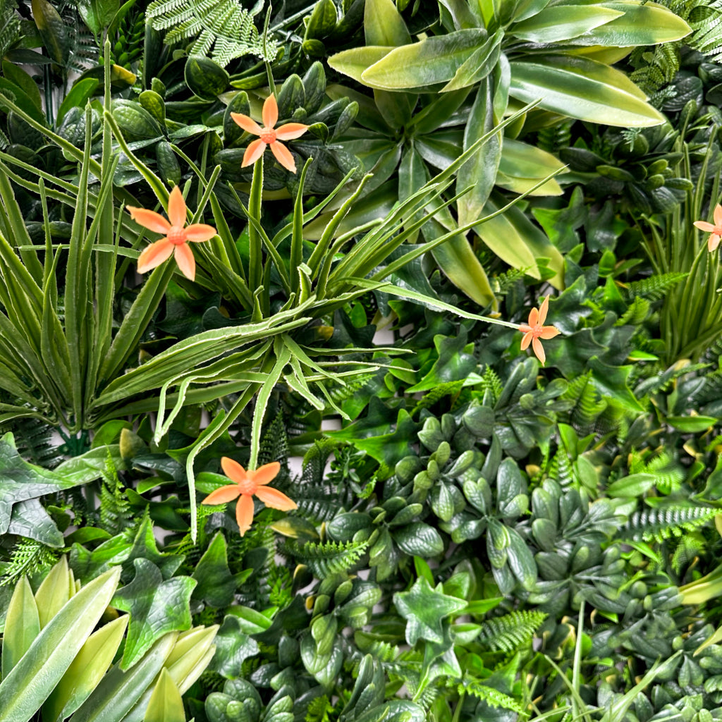 Artificial green wall panel with variegated greens of ivy, ferns, palm heads, grasses & small orange flowers 100x100 cm