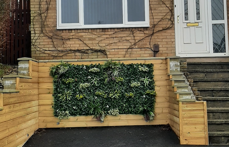 Artificial green wall panel with variegated green, red,  white & yellow foliage with ferns, palm heads, grasses & white flowers  100x100 cm