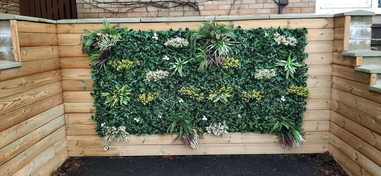 Artificial green wall panel with variegated green, red,  white & yellow foliage with ferns, palm heads, grasses & white flowers  100x100 cm