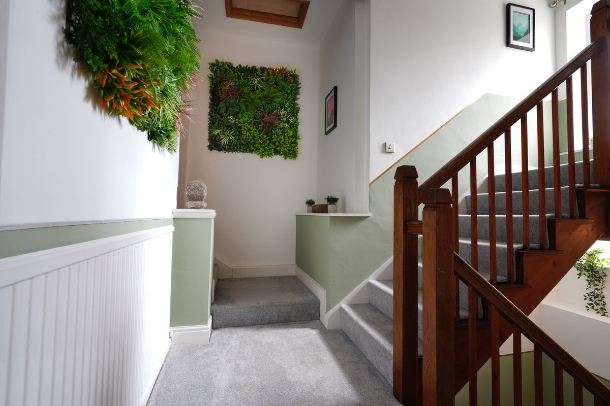 Artificial green foliage wall panel with dense leaves and small orange-red accents