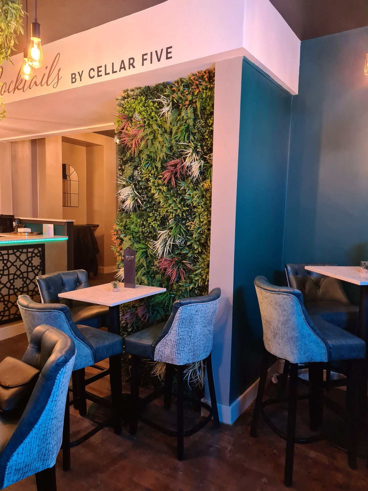 Artificial foliage feature wall panel with mixed green leaves and orange-red accents