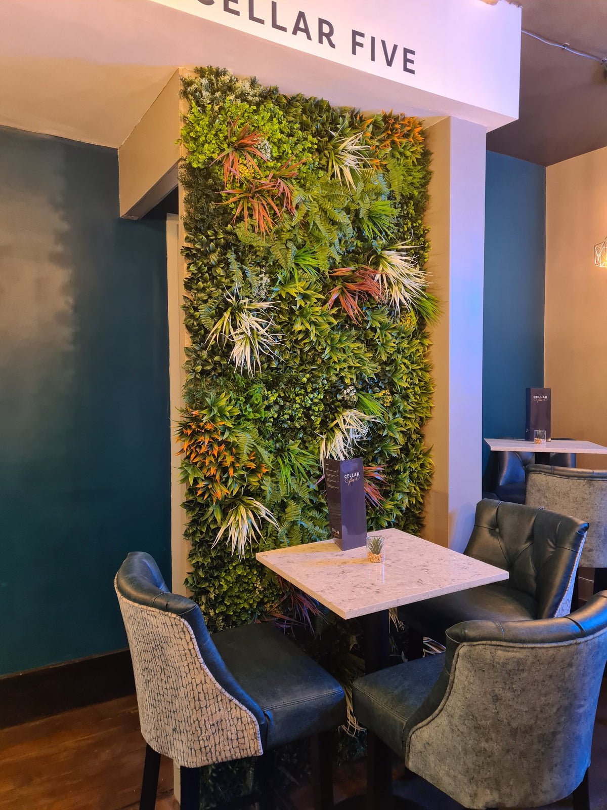 Vertical artificial foliage wall panel with dense green leaves and orange-red highlights