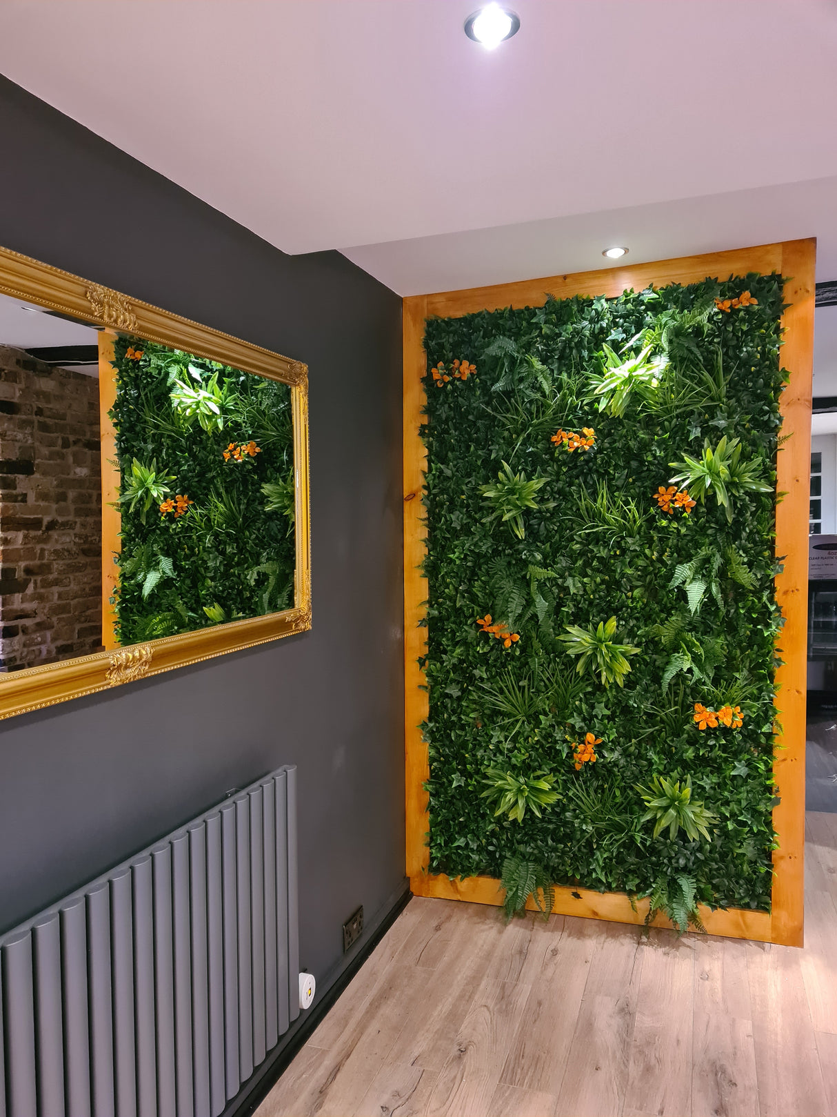 Artificial green wall panel with variegated greens of ivy, ferns, palm heads, grasses